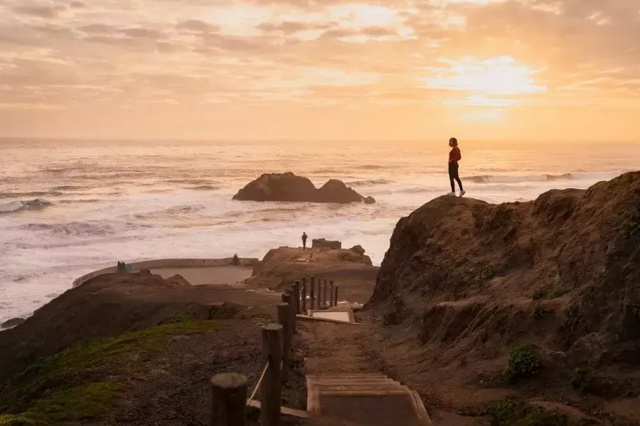 Zwei Menschen stehen auf Felsen mit Blick auf das Meer in den Sutro Baths in San Francisco.